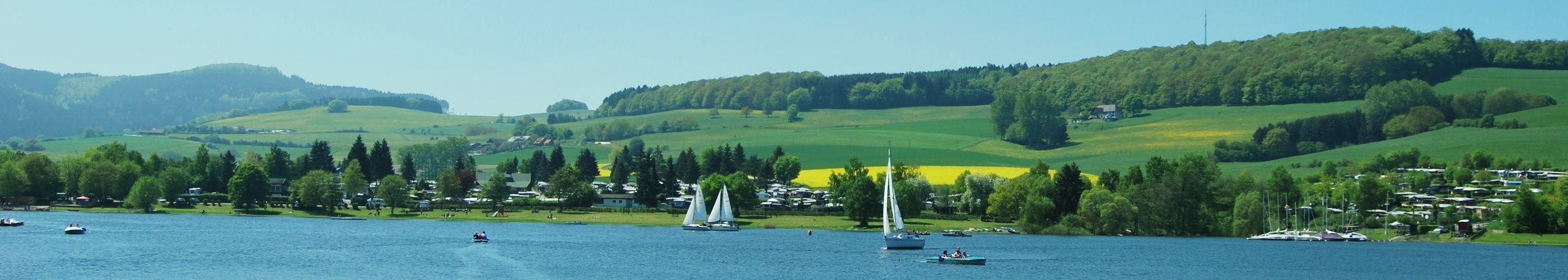 Diemelsee panoramisch uitzicht vanaf het water naar het strand en zeilboten