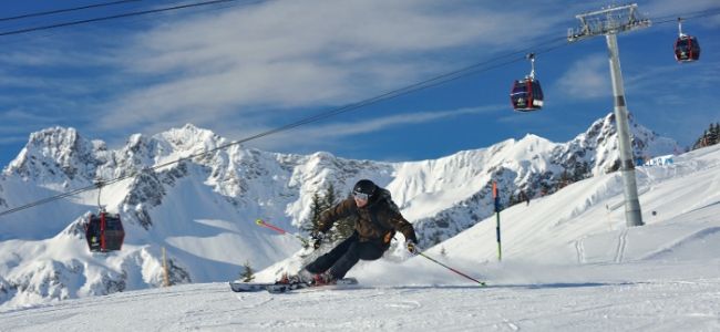 rasanter alpiner Skifahrer vor Seilbahn und Bergkulisse